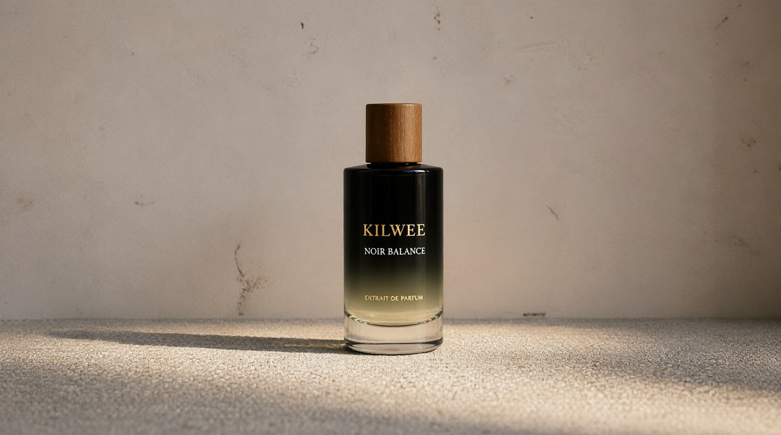 Perfume bottle labeled Kilwee Noir Balance with a wooden cap, black gradient bottle on a textured beige surface.