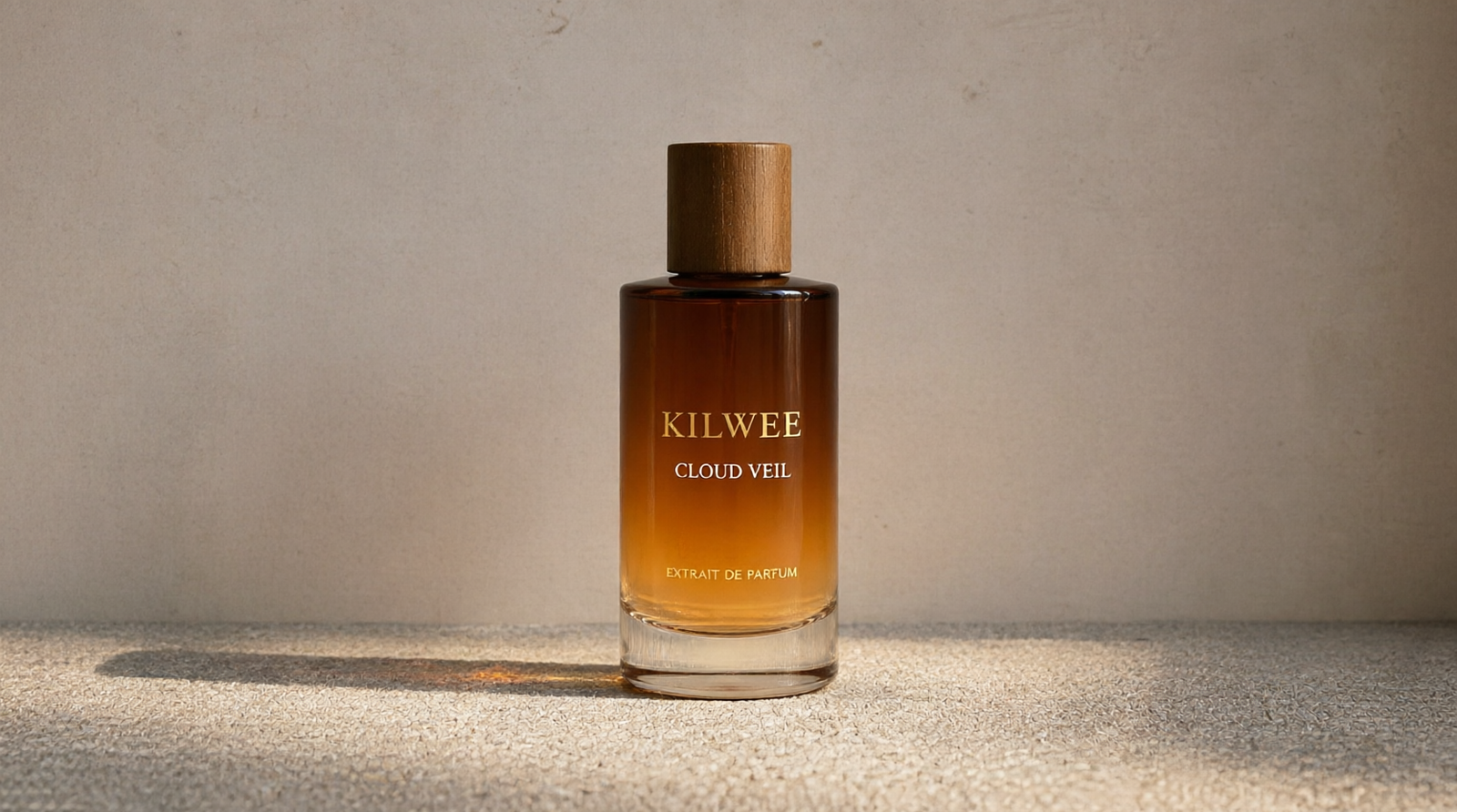 Kilwee Cloud Veil perfume bottle with a wooden cap, amber gradient glass, sitting on a textured gray surface.